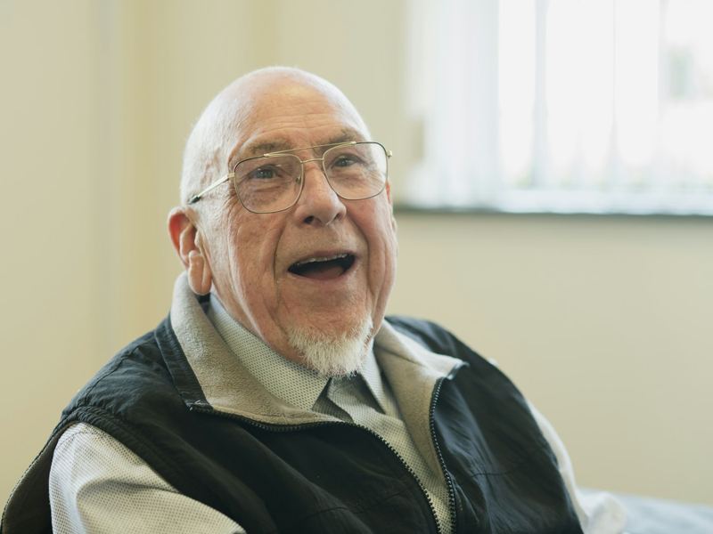 An older man in glasses laughing