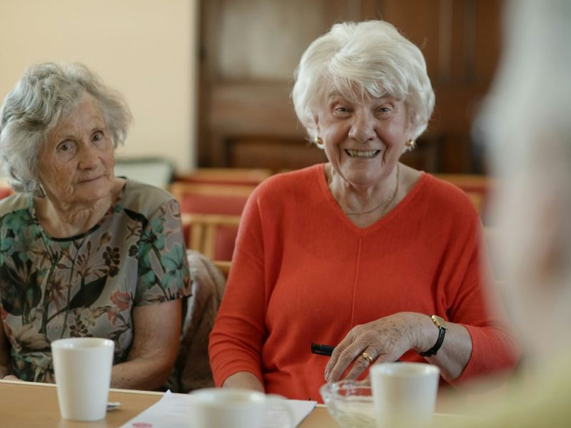 Two older women at a table, one laughing